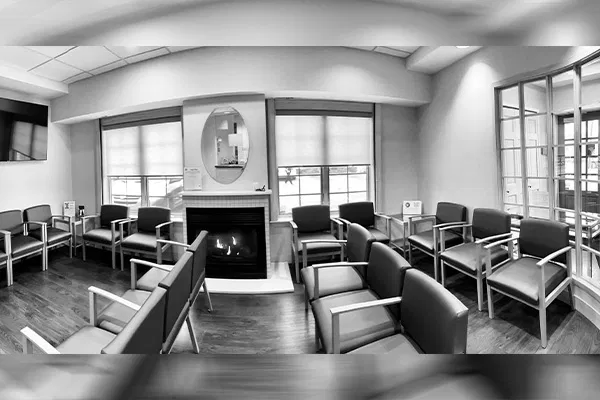 Modern dental waiting room with fireplace, contemporary furniture, and large windows in professional office setting.