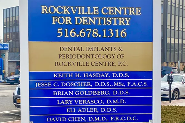 Rockville Centre dental practice sign displaying office name, phone number, services, and dentist names.