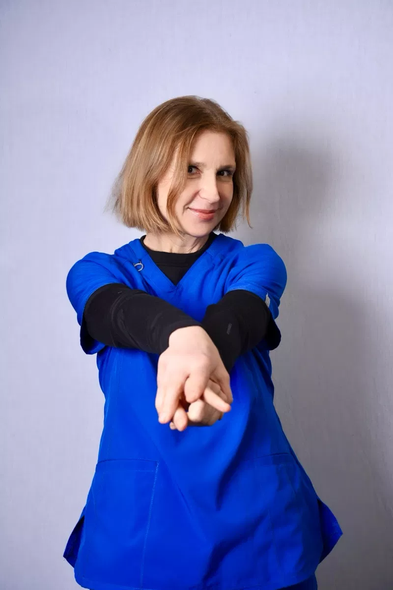 Young child in blue shirt extending arm forward against white background for dental practice promotional photo.