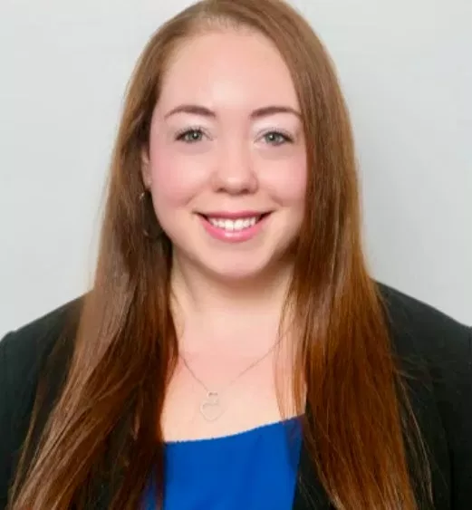 Young woman with long reddish-brown hair smiling at camera in professional headshot.