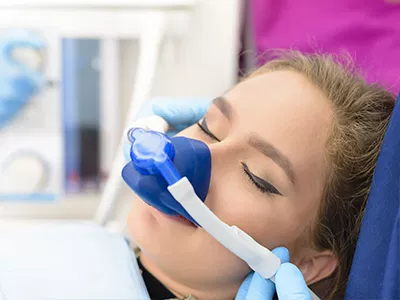 Patient receiving dental treatment with blue gloves and mask in modern dental office.